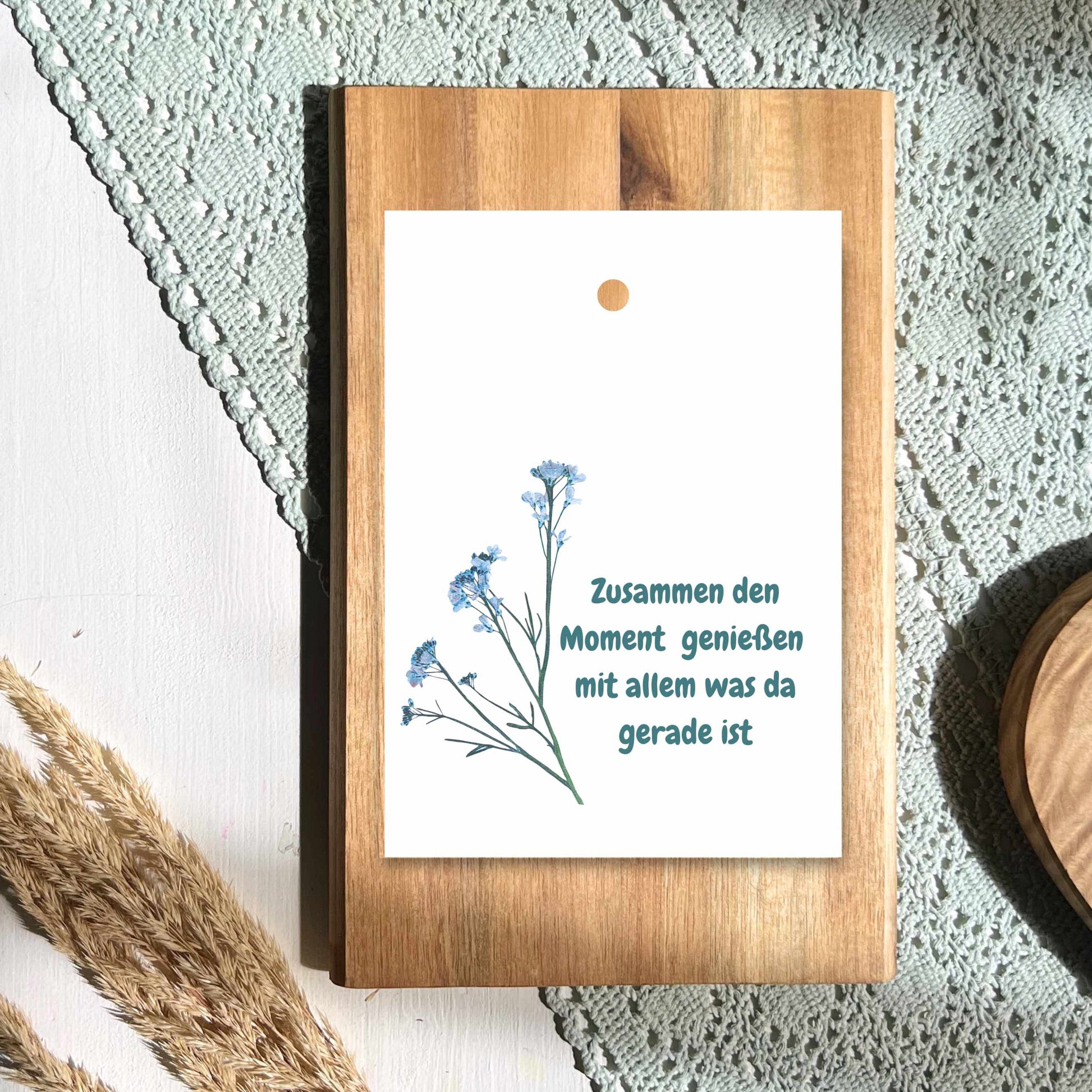 Geschenkanhänger aus Papier mit einem Bütenzweig und dem Text Zusammen dn Moment genießen mit allem was da gerade ist von foodigence