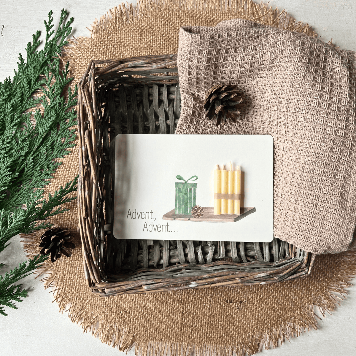 weihnachtliche Postkarten von foodigence mit echten Bienenwachskerzen zum Verschenken in der Weihnachtszeit "Advent, Advent..." mit 4 Kerzen auf einem Tablett - in einem Körbchen neben Tannengrün
