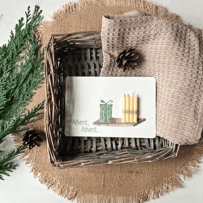 weihnachtliche Postkarten von foodigence mit echten Bienenwachskerzen zum Verschenken in der Weihnachtszeit "Advent, Advent..." mit 4 Kerzen auf einem Tablett - in einem Körbchen neben Tannengrün