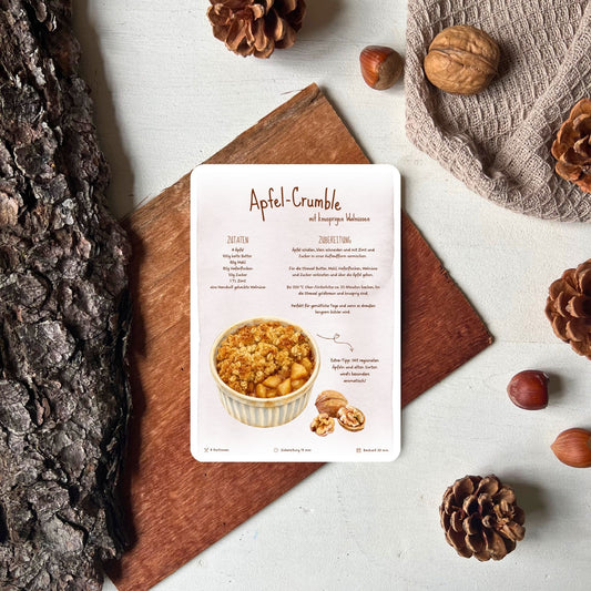 Rezept für Apfelcrumble als Rezeptkarte abgebildet vor herbstlicher Deko von foodigence