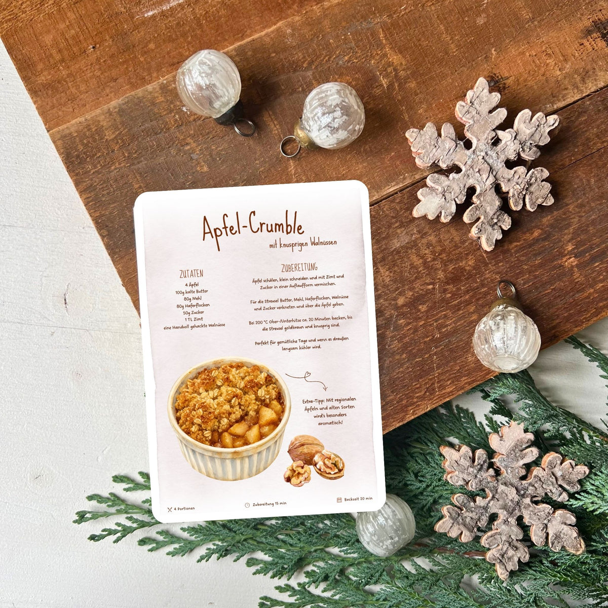 Apfelcrumble aus dem Ofen mit knusprigen Walnüssen als Rezeptkarte im Postkartenformat zum Verschenken und Nachbacken von foodigence dekoriert vor Weihnachtsdeko
