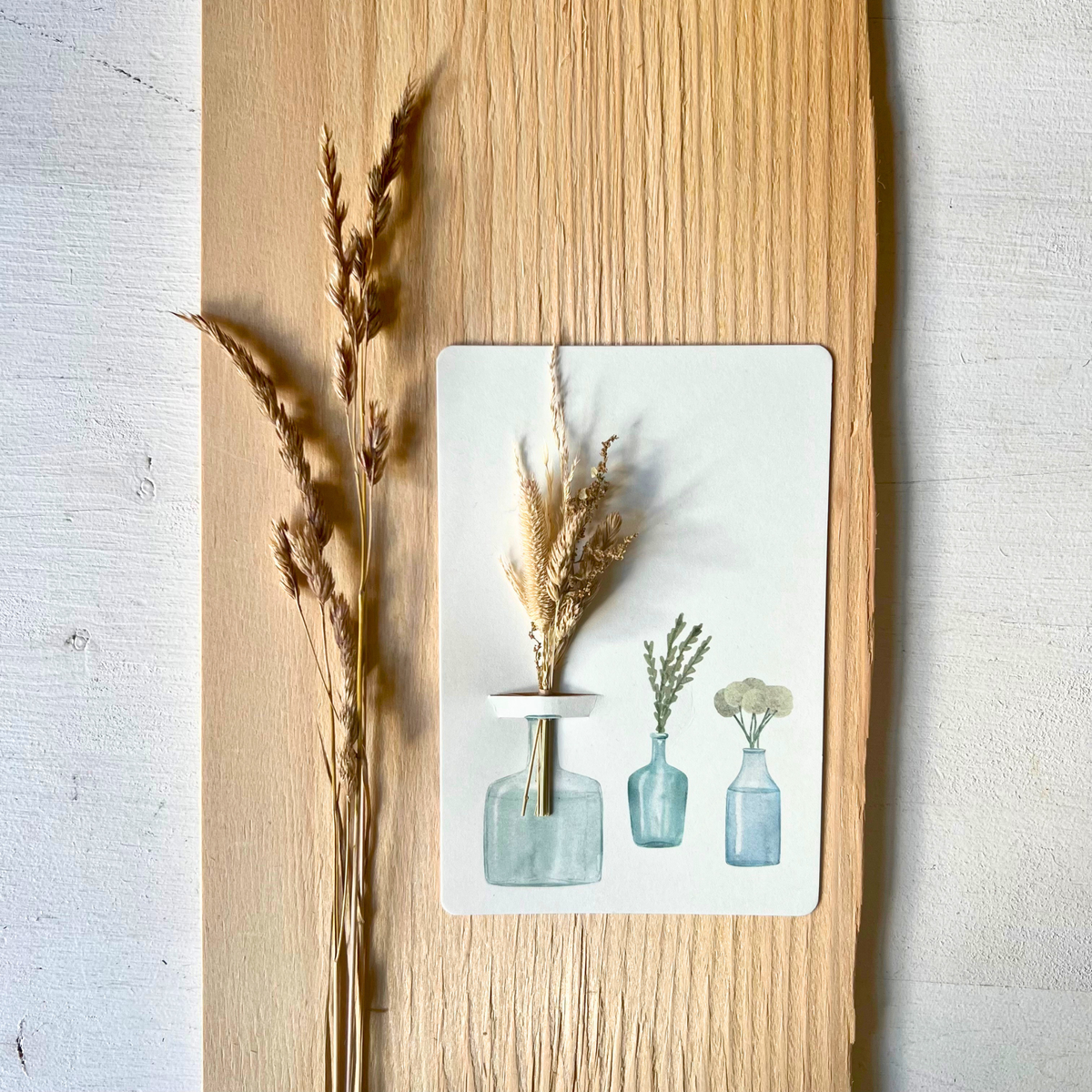 Postkarte von foodigence mit Sträußchen aus Wildgräsern in verschiedenen Vasen dekoeriet vor einer hellen Holzplatte