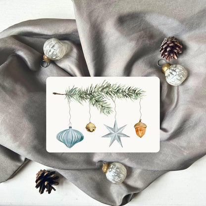 Weihnachtspostkarte von foodigence mit türkisen Weihnachtselementen in aquarell-Design vor einem grauen Samttuch abgebildet 