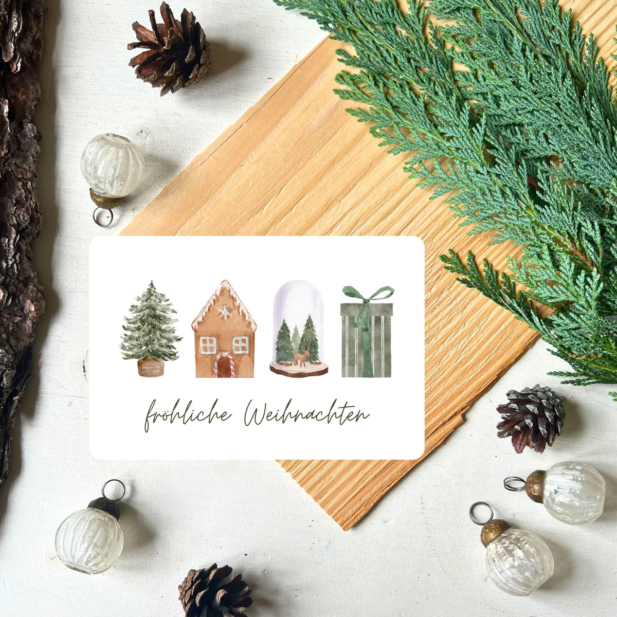 Karte mit weihnachtlichen Motiven (Tannenbaum, Lebkuchenhaus, Glaskugel, Geschenk) in grün/braun Design aus dem Weihnachtspostkarten Set von foodigence