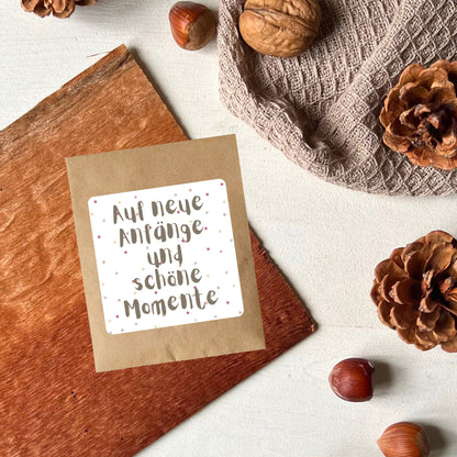 Samentütchen dekoriert mit Tannenzapfen auf dem steht: "Auf neue Anfänge und schöne Momente" um Vreschenken von foodigence