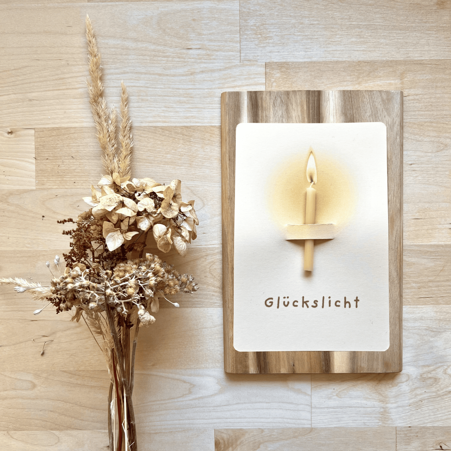 Postkarte mit Bienenwachskerze "Glückslicht" neben Deko 
