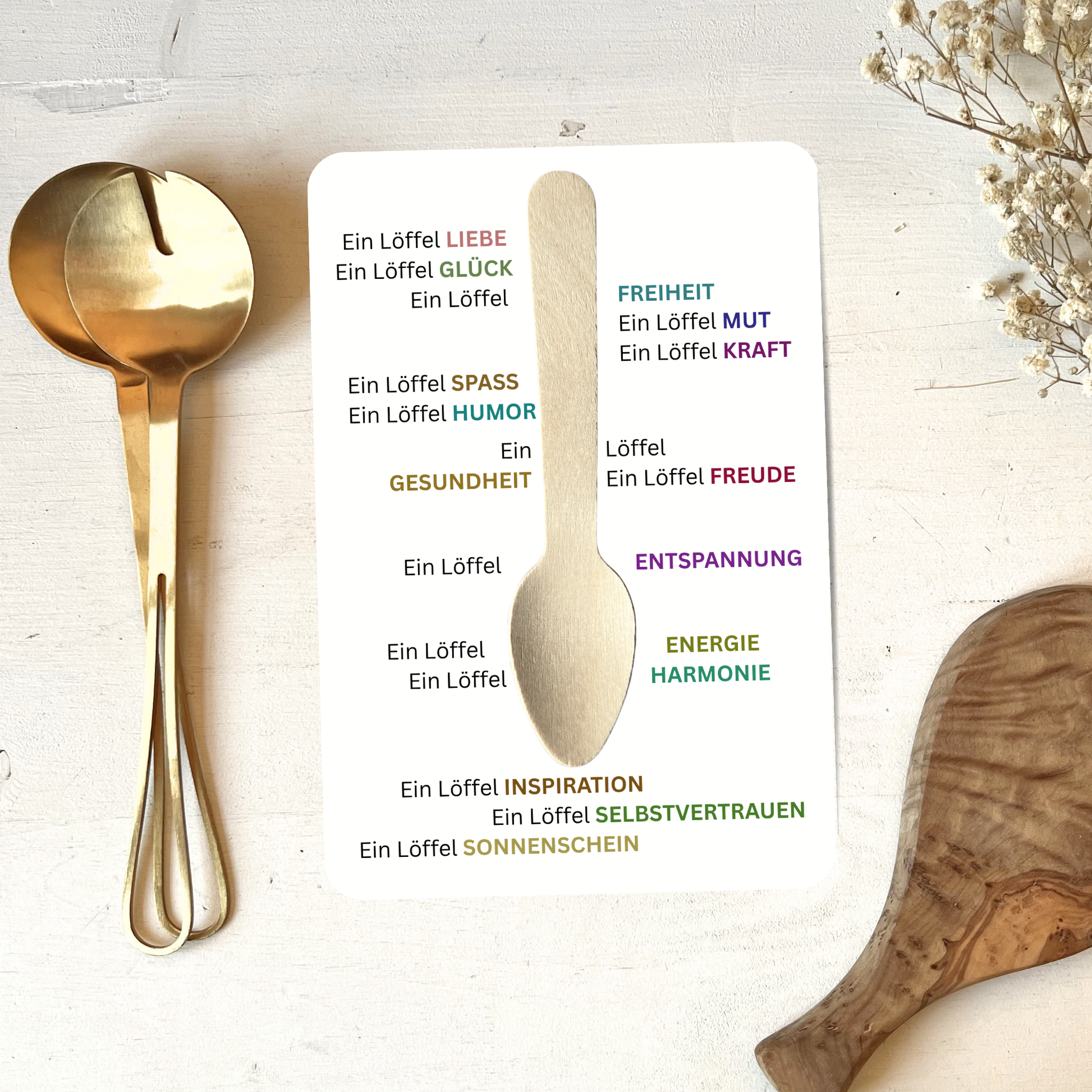 Postkarte mit echtem Holzlööfel neben goldenem Besteck liegend