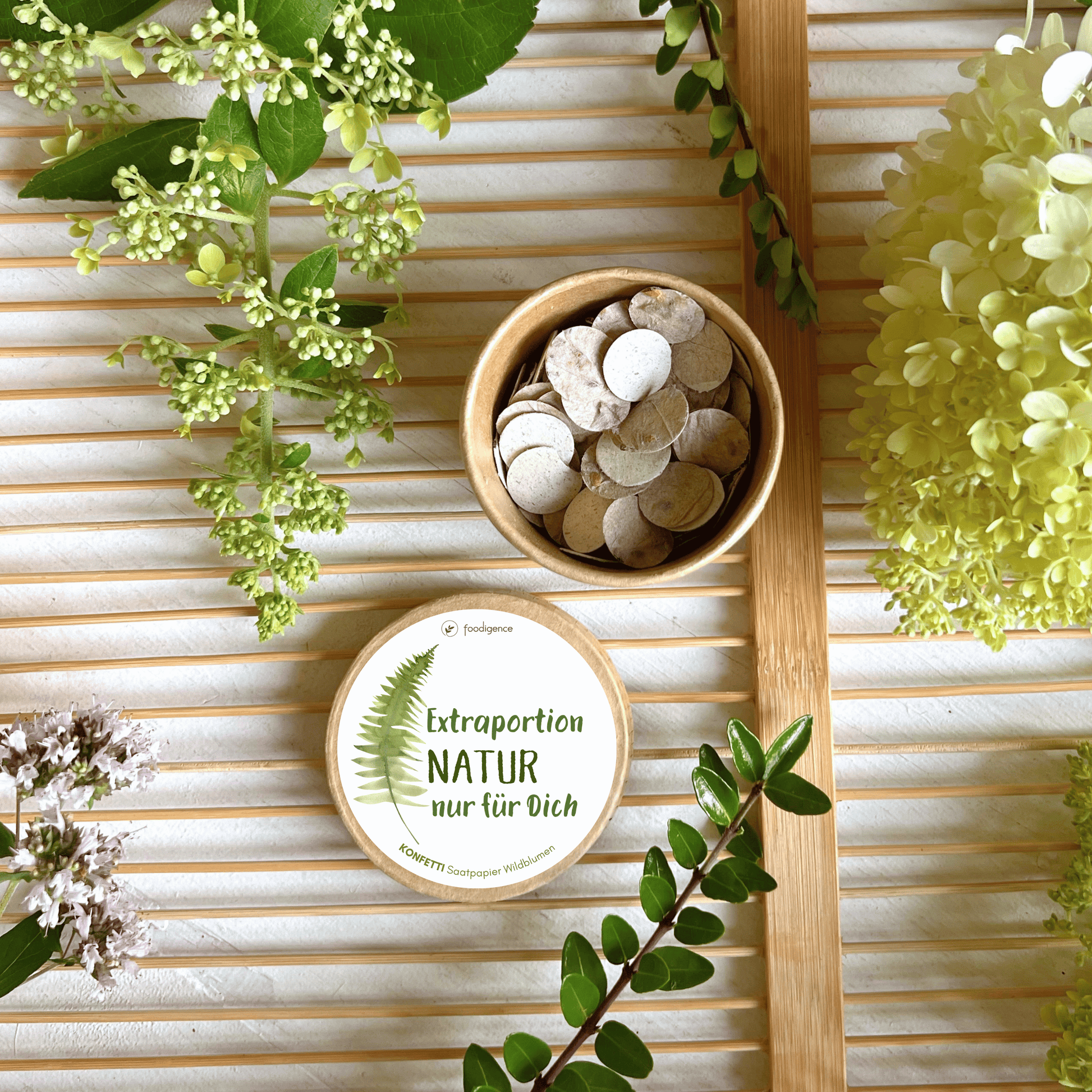 Saatkonfetti "Extraportion Natur nur für dich" offen umgeben von Blumen